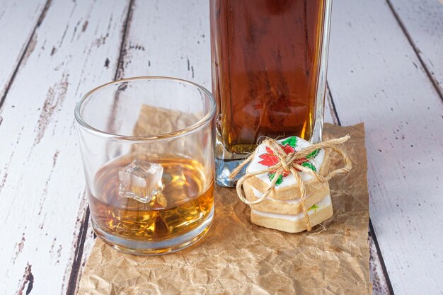 Glas Whisky mit Eis auf braunem Papier neben Butterkeksen.