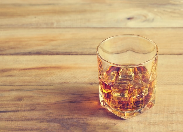 Glas Whisky mit Eis auf hölzernem Hintergrund