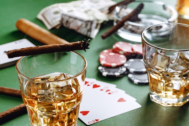 Glas Whisky-Zigarren-Spielkarten und Chips auf grüner Oberfläche
