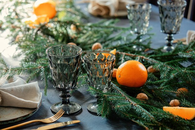 Glasbecher auf dem Tisch neben einem Teller und Tanne zu Weihnachten