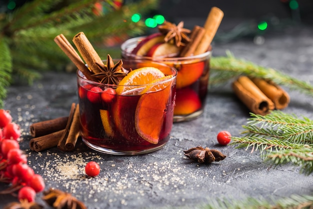 Glasbecher Glühwein mit Gewürzen und Zitrusfrüchten. Traditionelles Heißgetränk oder Getränk, festlicher Cocktail zu Weihnachten oder Neujahr