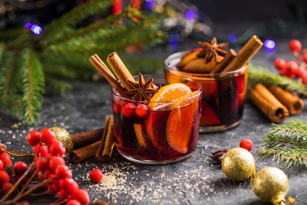 Glasbecher Glühwein mit Gewürzen und Zitrusfrüchten. Traditionelles Heißgetränk oder Getränk, festlicher Cocktail zu Weihnachten oder Neujahr