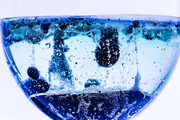 Glasbecher mit blauer Flüssigkeit und Blasen