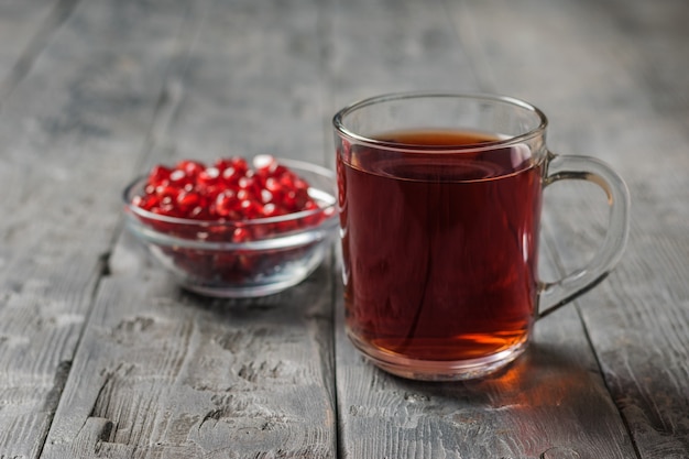 Glasbecher mit Granatapfelsaft und Granatapfelkernen auf einem schwarzen Holztisch. Trinken Sie nützlich für die Gesundheit.