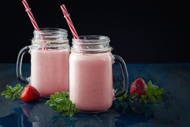 Glasbecher mit köstlichem Erdbeermilchshake auf einem schwarzen Tisch