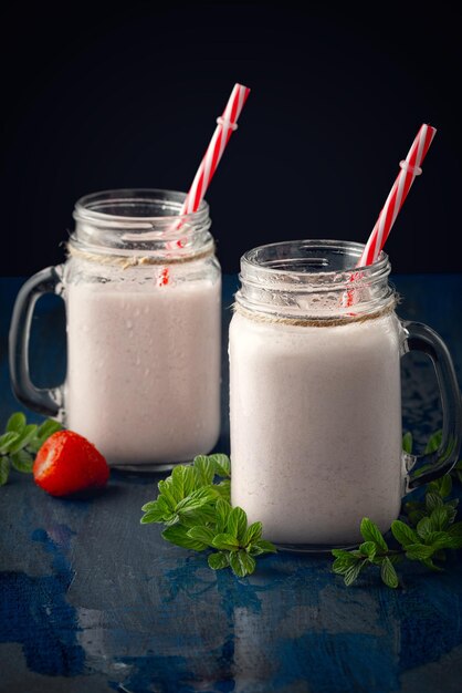 Glasbecher mit köstlichem Erdbeermilchshake auf einem schwarzen Tisch