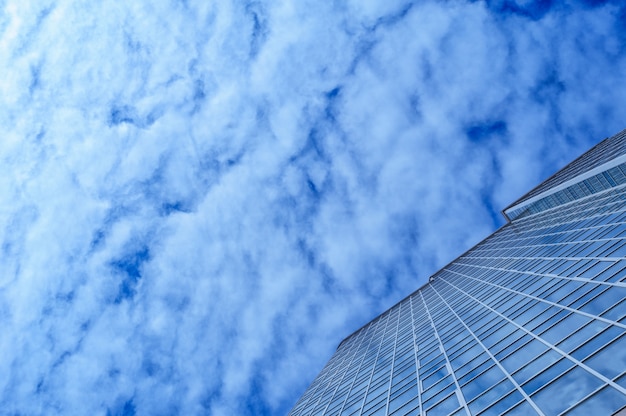 Glasbürogebäudewolkenkratzer auf einem Hintergrund von Wolken