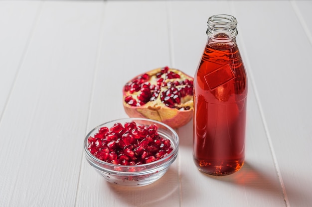 Glasflasche frischer Granatapfelsaft auf einem weißen Tisch. Trinken Sie nützlich für die Gesundheit.