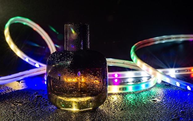 glasflasche für parfüm auf buntem led-lichthintergrund