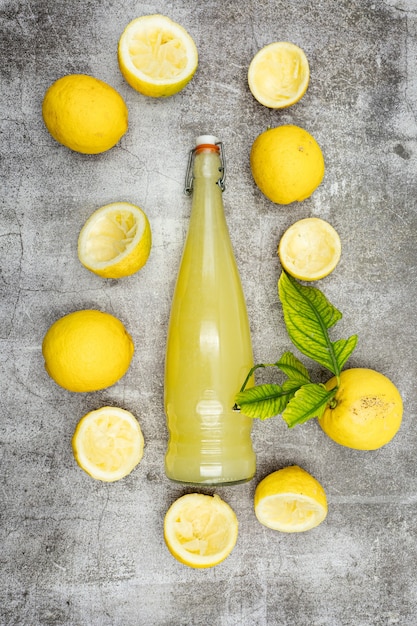 Glasflasche gefüllt mit Zitronensaft mit Zitronen herum