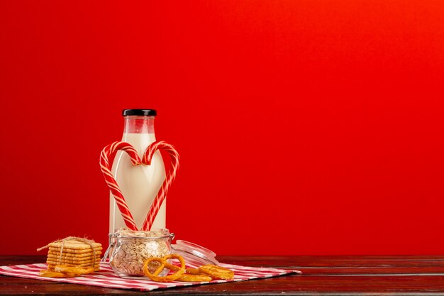 Glasflasche mit frischer Milch und Zuckerstangen auf Holztisch