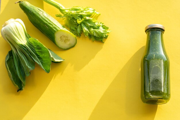 Glasflasche mit Gurken- und Sellerie-Smoothie auf gelbem Hintergrund