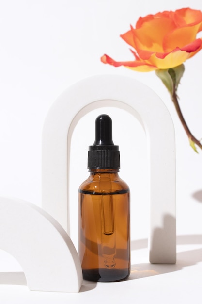 Glasflasche mit Serum im Bogen mit Rosenblüte Hyaluronsäure-Ölserum mit Kollagen und Peptiden Hautpflegeprodukt Mockup-Verpackung Kosmetikdesign-Branding