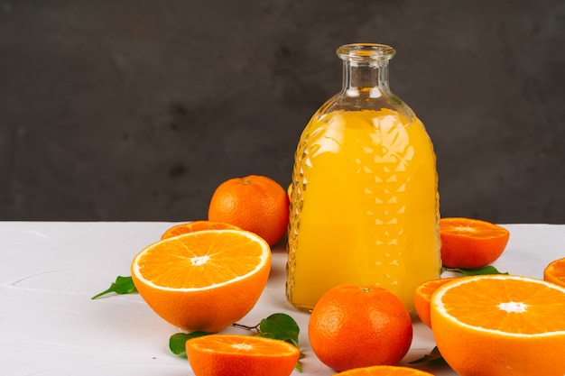 Glasflasche Orangensaft mit Hälften von reifen Orangen