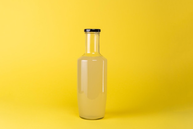 Glasflasche Zitronensaft isoliert auf gelbem Hintergrund