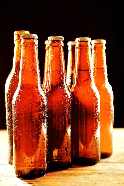 Glasflaschen Bier auf Holztisch auf dunklem Hintergrund