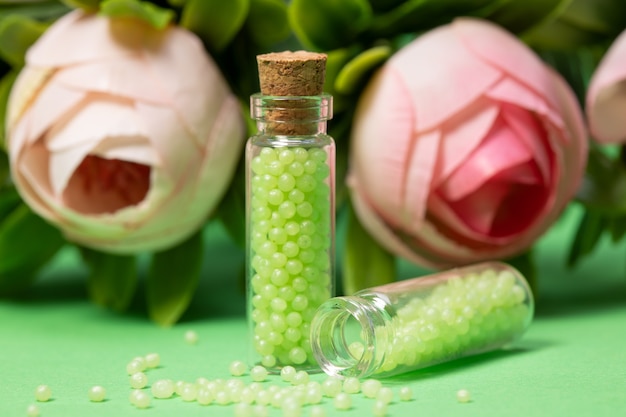 Glasflaschen mit grünem Granulat mit Rosen. Homöopathische Mittel