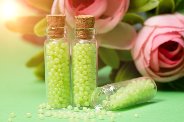 Glasflaschen mit grünem Granulat mit Rosen. Homöopathische Mittel