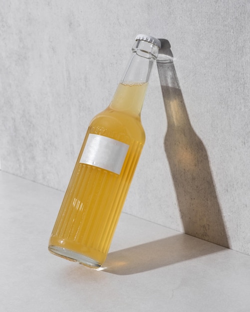 Foto glasflaschen mit leerem etikett und flüssigkeit ähnlich limonadenbier oder kombucha auf grauem hintergrund