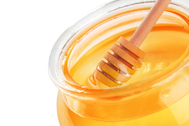 Glasgefäß mit dem süßen Honig lokalisiert auf weißem Hintergrund