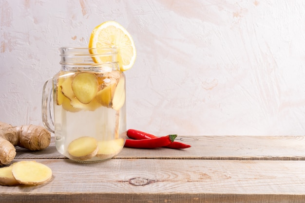 Glasgefäß mit Ingwerwasser auf Holztisch