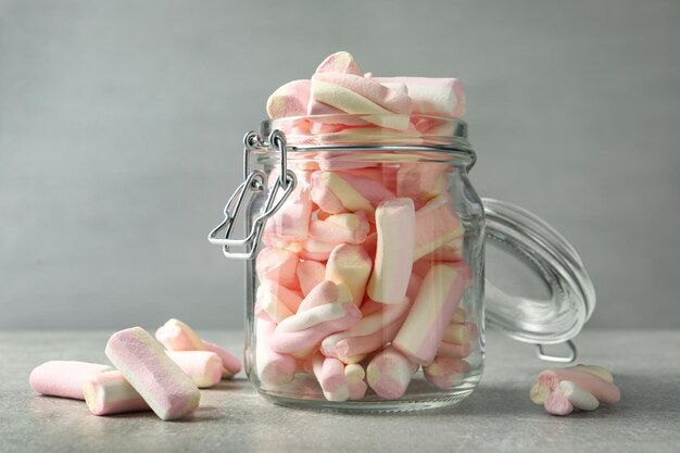 Glasgefäß mit leckeren Marshmallows auf hellgrauer Tischnahaufnahme