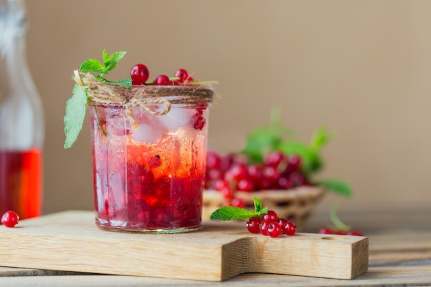 Glasgefäß mit Soda-Getränk der roten Johannisbeere auf Holztisch