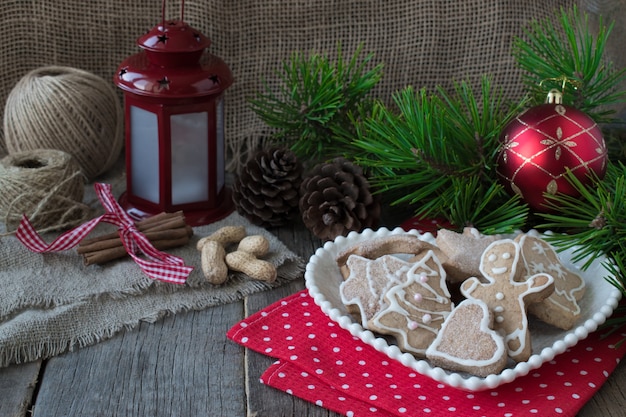 Glasierte hausgemachte Kekse auf dem Hintergrund von Weihnachtsbaumzweigen und einer Taschenlampe.