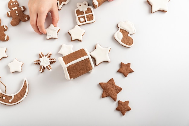 Glasierte Lebkuchenplätzchen auf einem weißen Tisch und einer Kinderhand. Vorbereitung auf Weihnachten. Ansicht von oben.