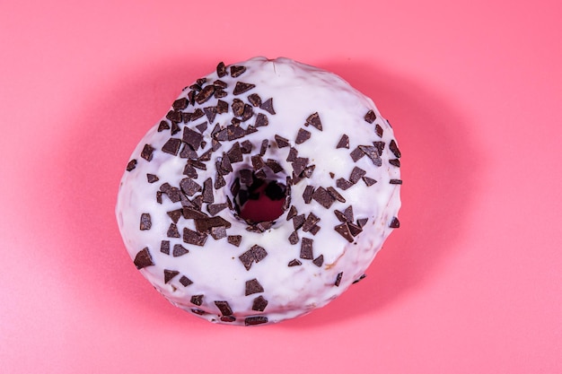 Glasierter Donut mit Schokoladenstückchen oben isoliert auf rosa Hintergrund