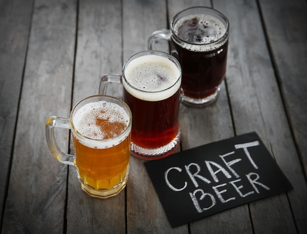 Glaskrüge mit verschiedenen Craft-Biersorten auf Holztisch