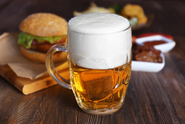 Glaskrug helles Bier mit Snacks auf dunklem Holztisch aus nächster Nähe