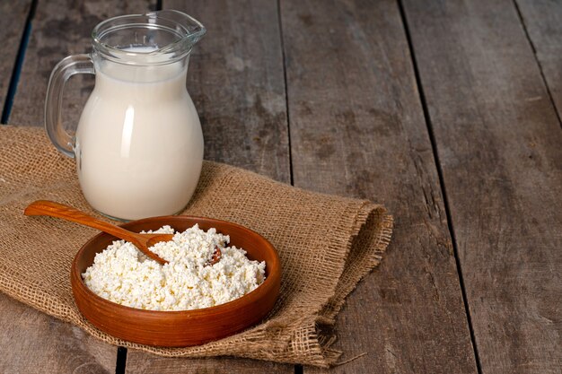 Glaskrug Milch und Schüssel Hüttenkäse auf Holztisch schließen oben