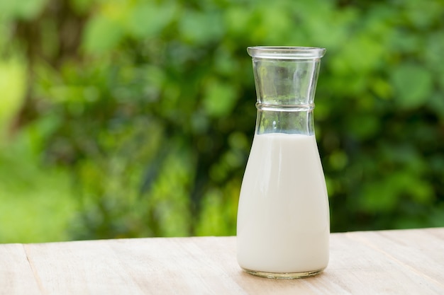 Glasmilchflasche mit Zusammenfassung verwischte Waldnaturhintergrund