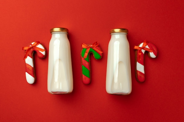 Glasmilchflasche und Weihnachtslebkuchenplätzchen auf rotem Hintergrund