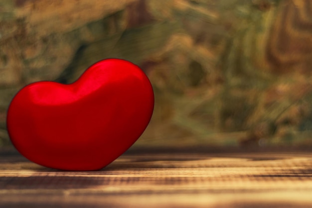Glasrotes Herz auf einem alten Holztisch Schöner dunkler Hintergrund