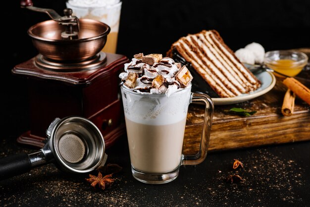 Glasschale mit Kaffee mit Sahne und Schokolade auf Schwarz