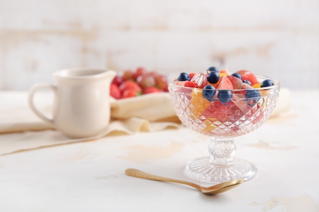 Glasschale mit leckerem Obstsalat auf dem Tisch