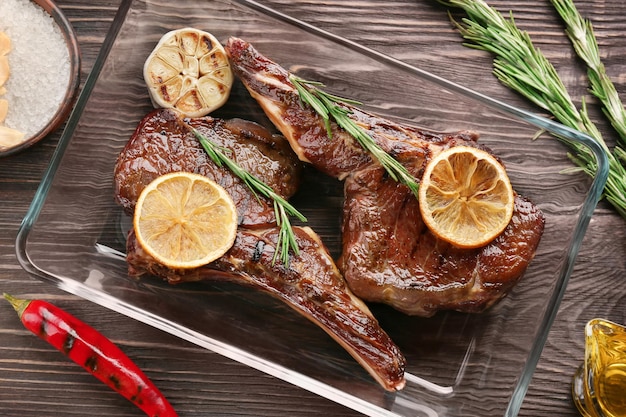 Glasschale mit leckeren gegrillten Steaks auf Holztisch