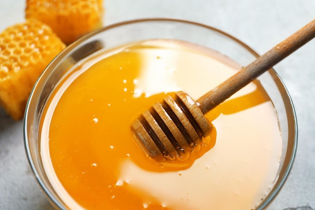 Glasschüssel mit köstlichem Honig und Schöpflöffel auf dem Tisch