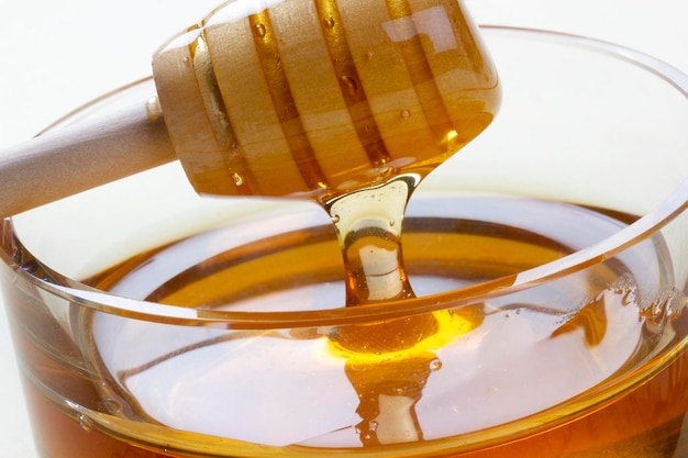 Glasschüssel voller Honig Honiglöffel aus Holz