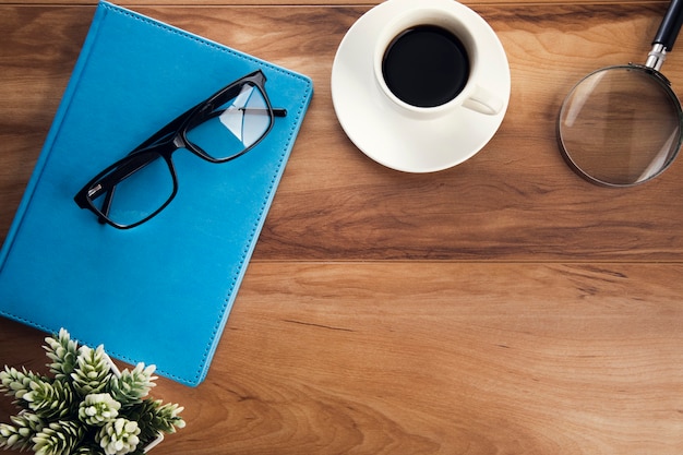 Glasseson Buch mit Tasse Kaffee und Lupe auf dem Tisch