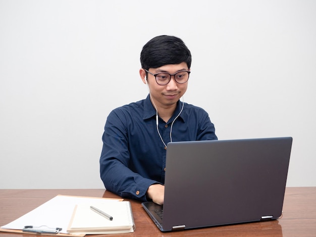 Glassses hombre usando una computadora portátil para trabajar en la mesa de su sala de trabajo