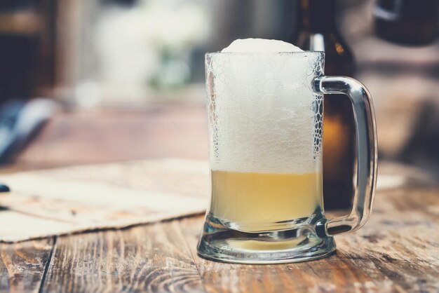 Glastasse Bier mit Schaum auf dem Holztisch