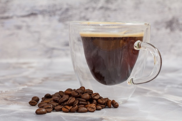 Glastasse Kaffee und geröstete Kaffeebohnen auf dem Küchentisch