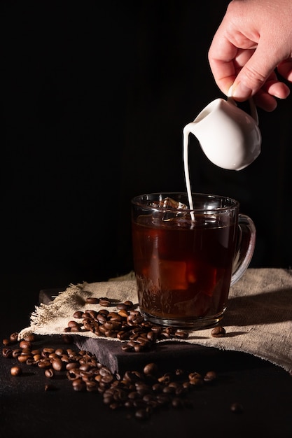 Glastasse mit kaltem Kaffee und Eis, Kaffeebohnen