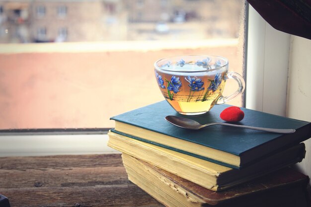 Glastasse Tee auf Büchern am Fenster