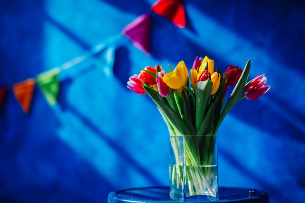 Glasvase mit Blumenstrauß von roten, gelben und rosa Tulpen