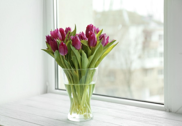 Glasvase mit Strauß schöner Tulpen auf der Fensterbank