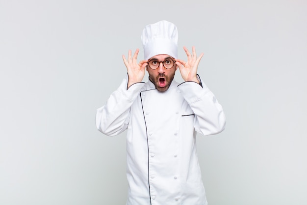 Glatze Mann fühlte sich schockiert, erstaunt und überrascht und hielt eine Brille mit einem erstaunten, ungläubigen Blick